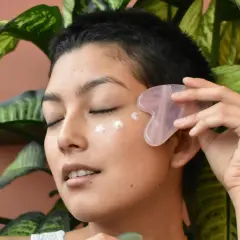 Frau mit Gua Sha Stein und Creme am Auge, genießt die feuchtigkeitsspendende Tremella Wirkung für strahlende Haut.