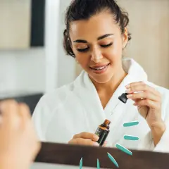 Frau im Bademantel nutzt ein Serum mit polyglutamic acid für strahlende Haut.