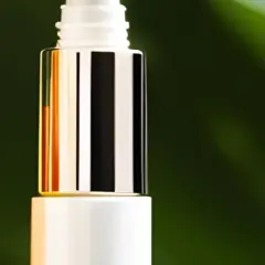 Zwei luxuriöse Flaschen mit Seren, die Glykolsäure und Retinol enthalten, vor einem grünen Blatt.