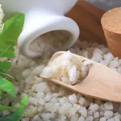 Magnesiumsulfat-Kristalle auf einem Holzlöffel, die die entspannende Wirkung von Magnesiumsulfat für ein wohltuendes Bad andeuten.
