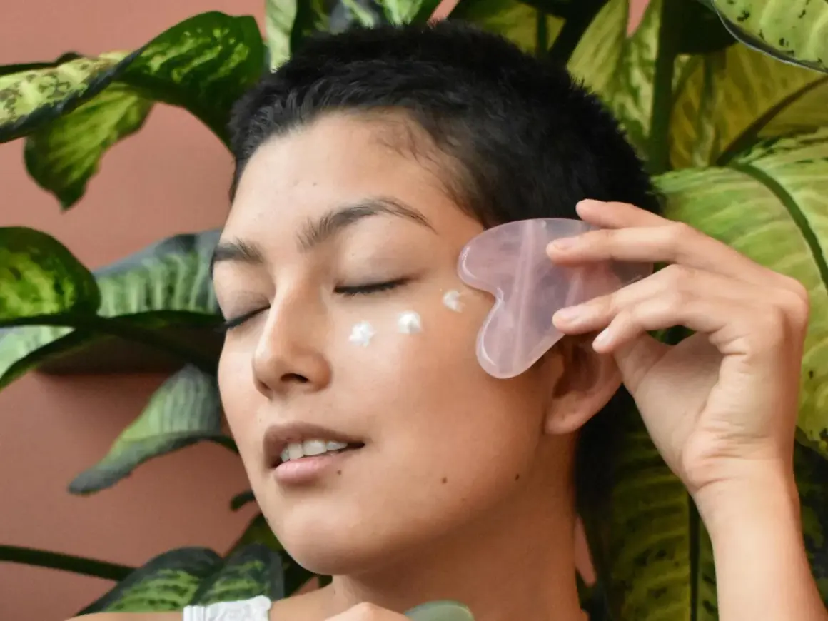 Frau mit Gua Sha Stein und Creme am Auge, genießt die feuchtigkeitsspendende Tremella Wirkung für strahlende Haut.