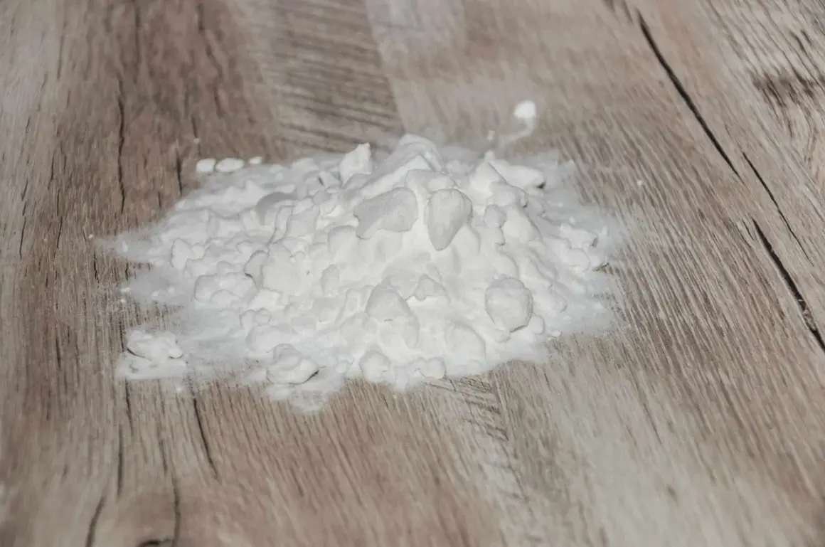 Ein Haufen weißes Pulver, wahrscheinlich Natriumascorbylphosphat, liegt auf einer Holzoberfläche.