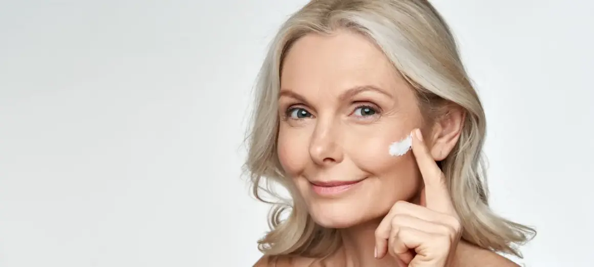 Eine Frau trägt Sonnencreme auf, um Falten vorzubeugen. Jeden Tag Sonnencreme gegen Falten schützt die Haut.
