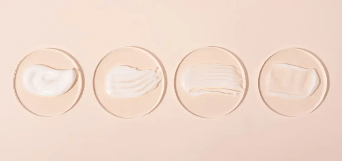 Vier Cremeproben auf Glasplättchen: eine reichhaltige, eine seidige, eine gestreifte und eine transparente. Ideal für Hautpflege mit niacinamide und vitamin c.